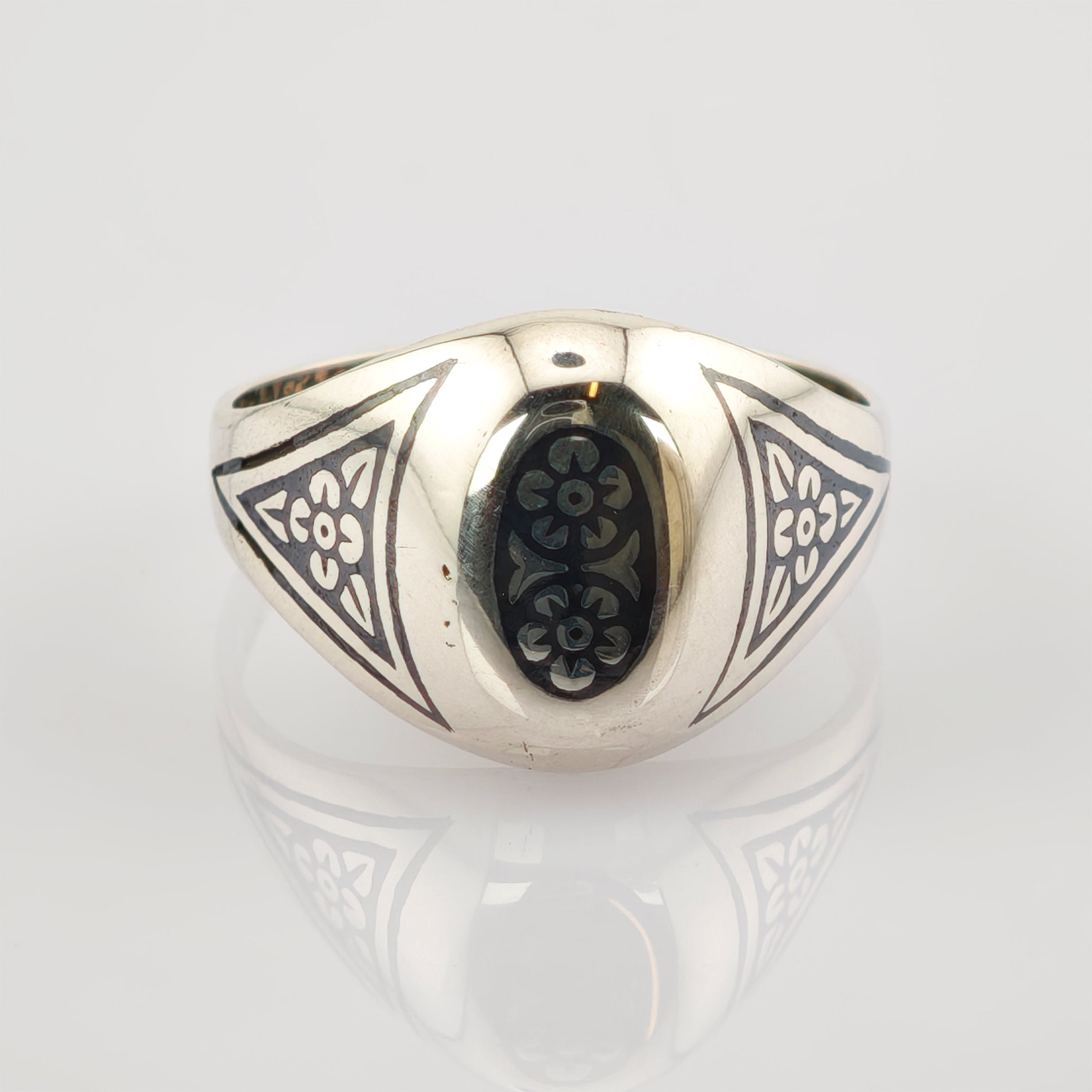Silberner Ring mit ovalem schwarzen Mittelstück und weißen Blumenmustern in Dreiecksform