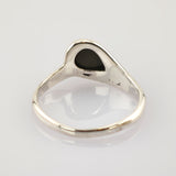 Silberner Ring mit polierter Oberfläche und schwarzer tropfenförmiger Einlage auf weißem spiegelndem Untergrund