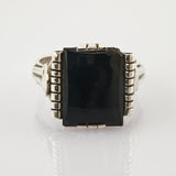 Silberner Ring mit großer rechteckiger schwarzer Steinfassung und geteiltem Ringband auf weißem Hintergrund