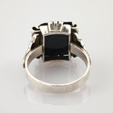 Silberner Ring mit rechteckigem schwarzem Stein und kunstvoller Metallarbeit an den Seiten
