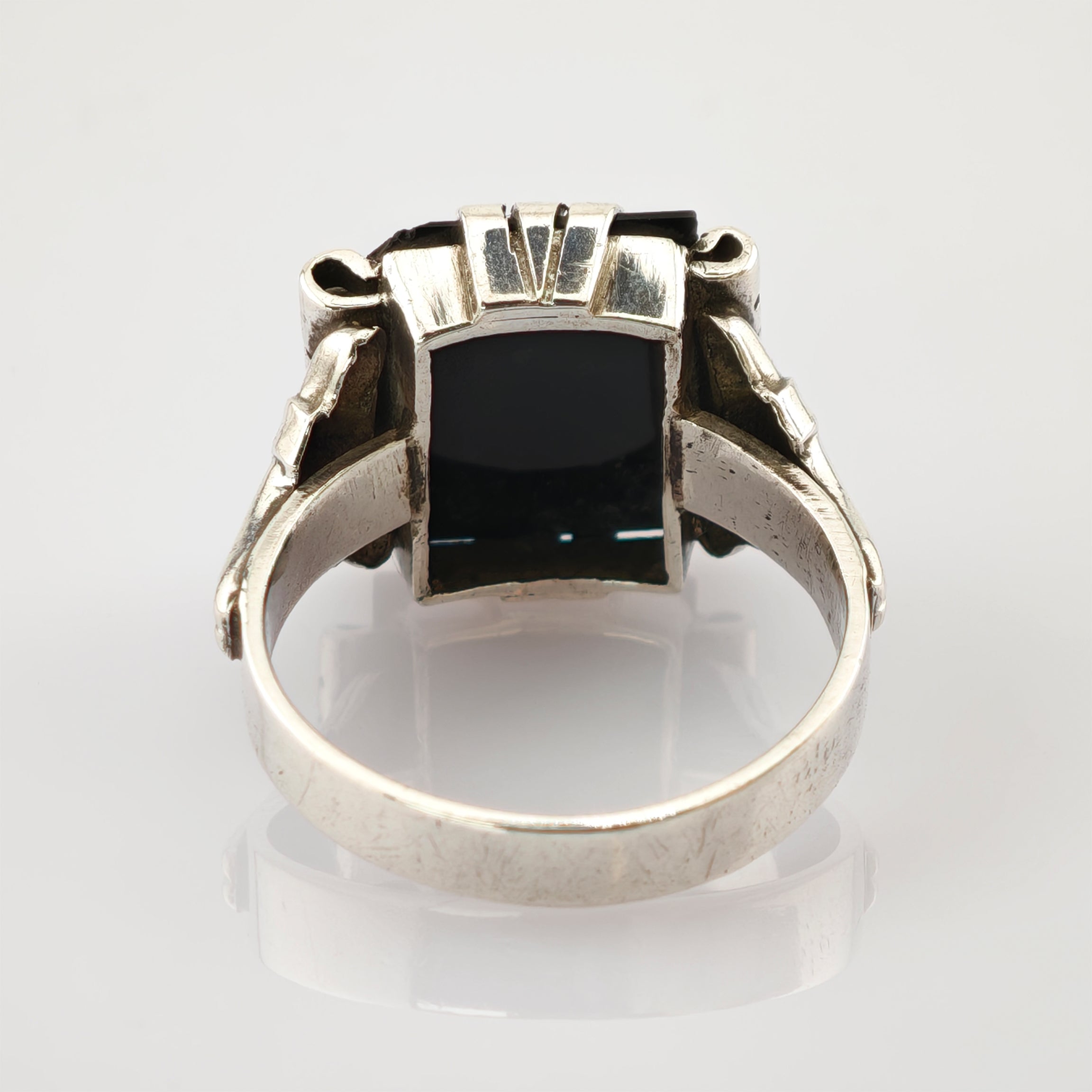 Silberner Ring mit rechteckigem schwarzem Stein und kunstvoller Metallarbeit an den Seiten