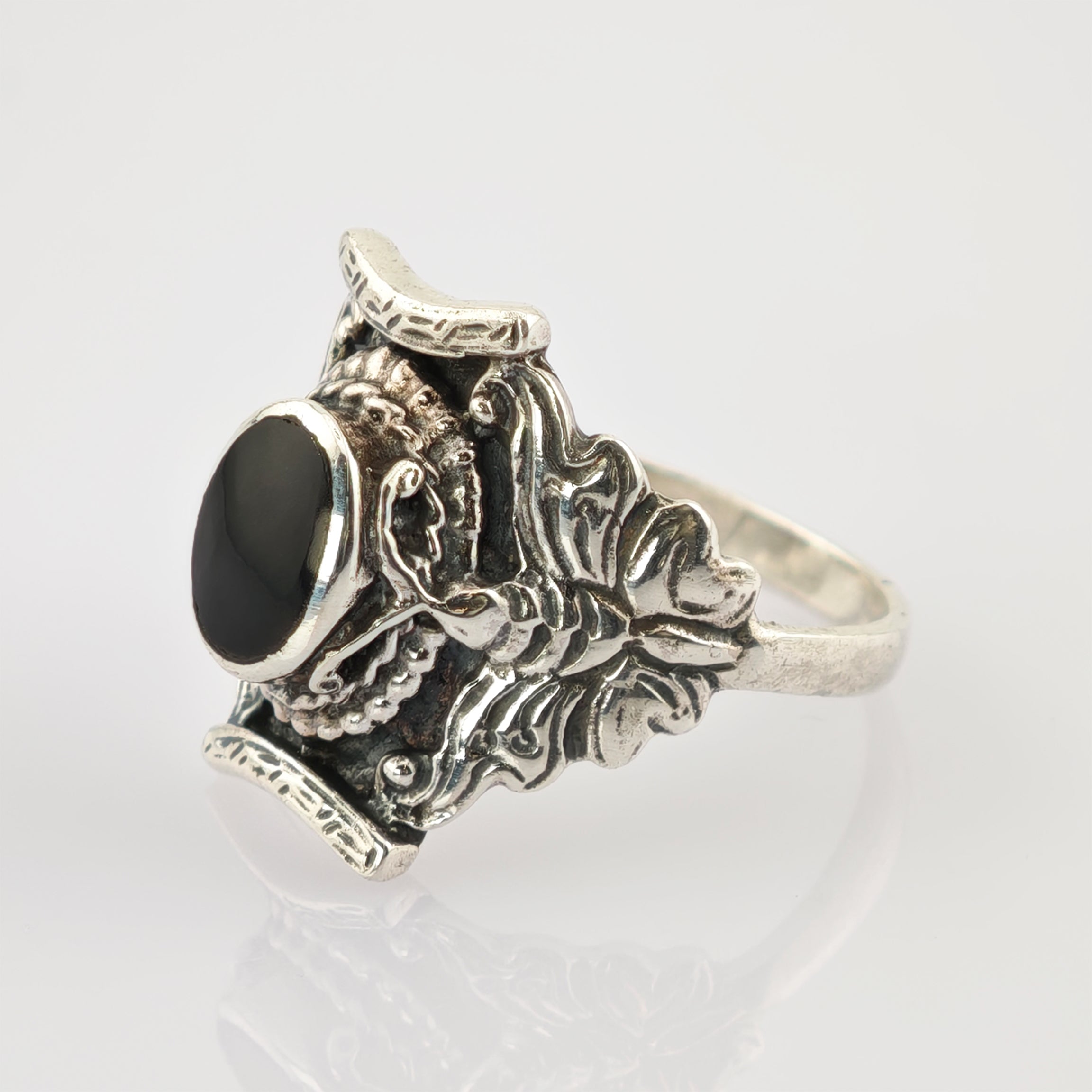 Silberner Ring mit kunstvollem Design und ovalem schwarzen Stein.