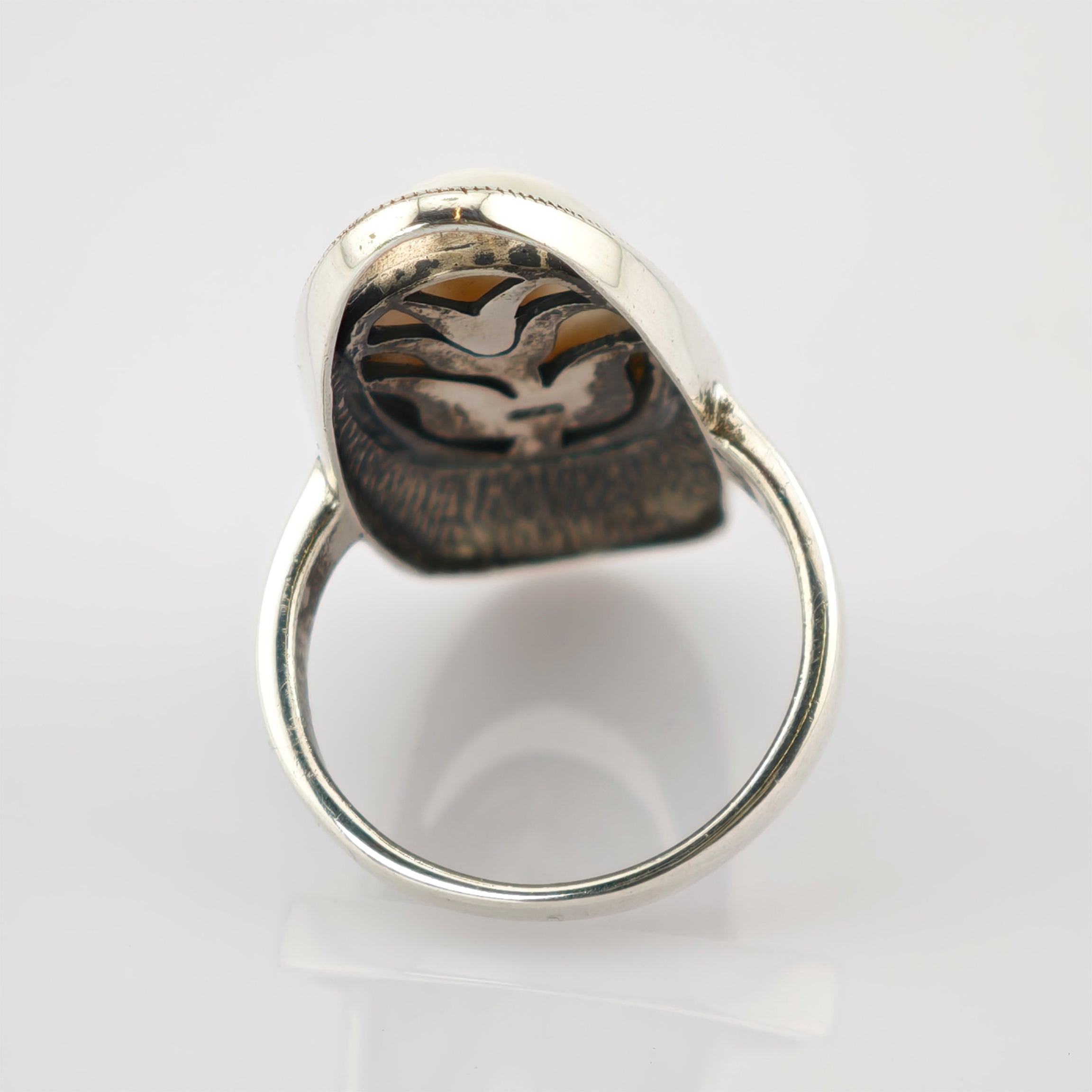 Silberner Ring mit graviertem Vogel-Emblem auf Zweig, oxidiertes Design auf weißem Hintergrund.