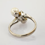 Silberner Ring mit weißer Perle und filigraner Metallverzierung am Ringkopf.