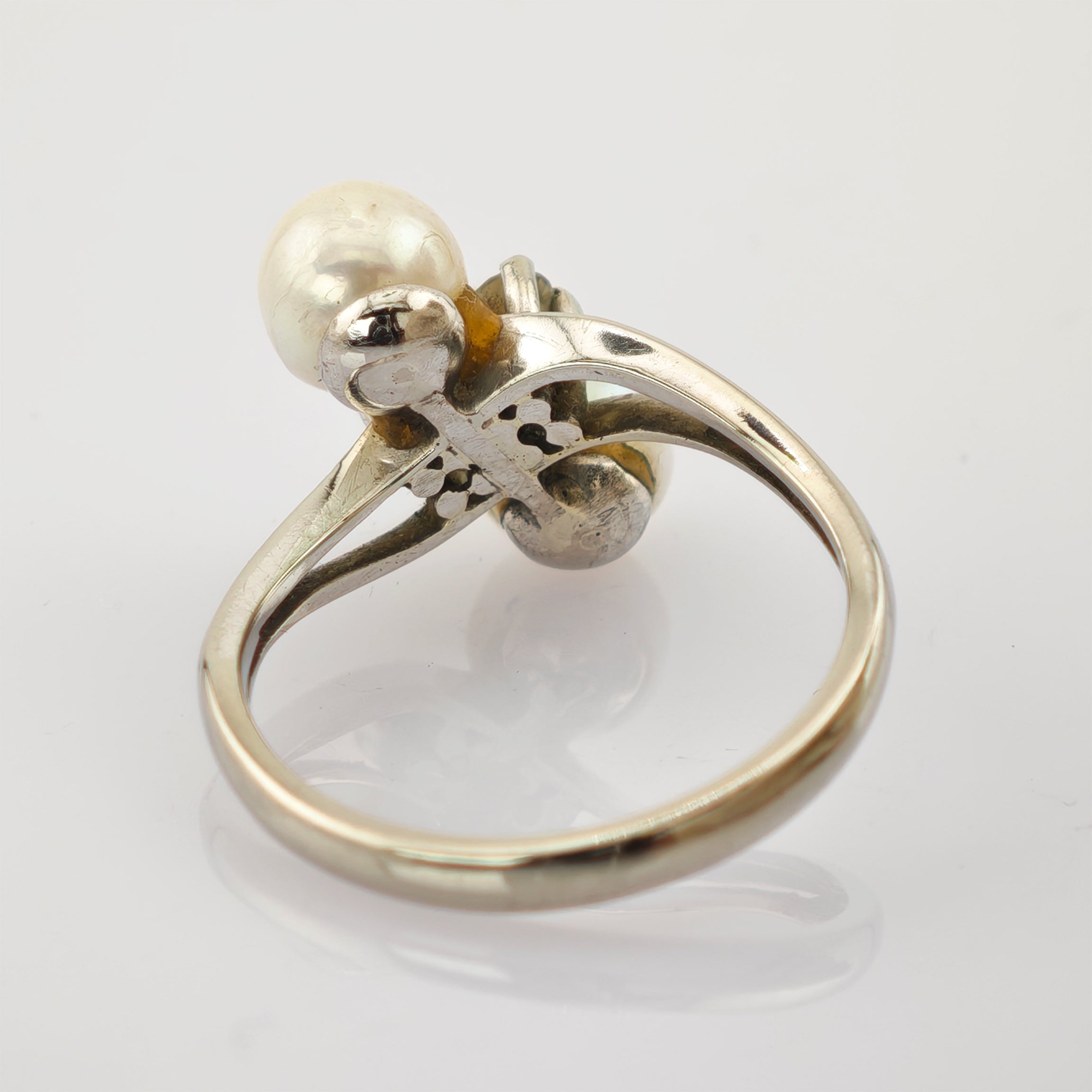 Silberner Ring mit weißer Perle und filigraner Metallverzierung am Ringkopf.