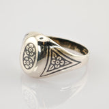 Silberner Siegelring mit schwarzen floralen Gravuren und der Zahl 7 auf weißem Hintergrund