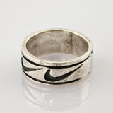 Silberner Vintage-Ring mit dunkel gefülltem Muster und Gebrauchsspuren auf reflektierender Oberfläche