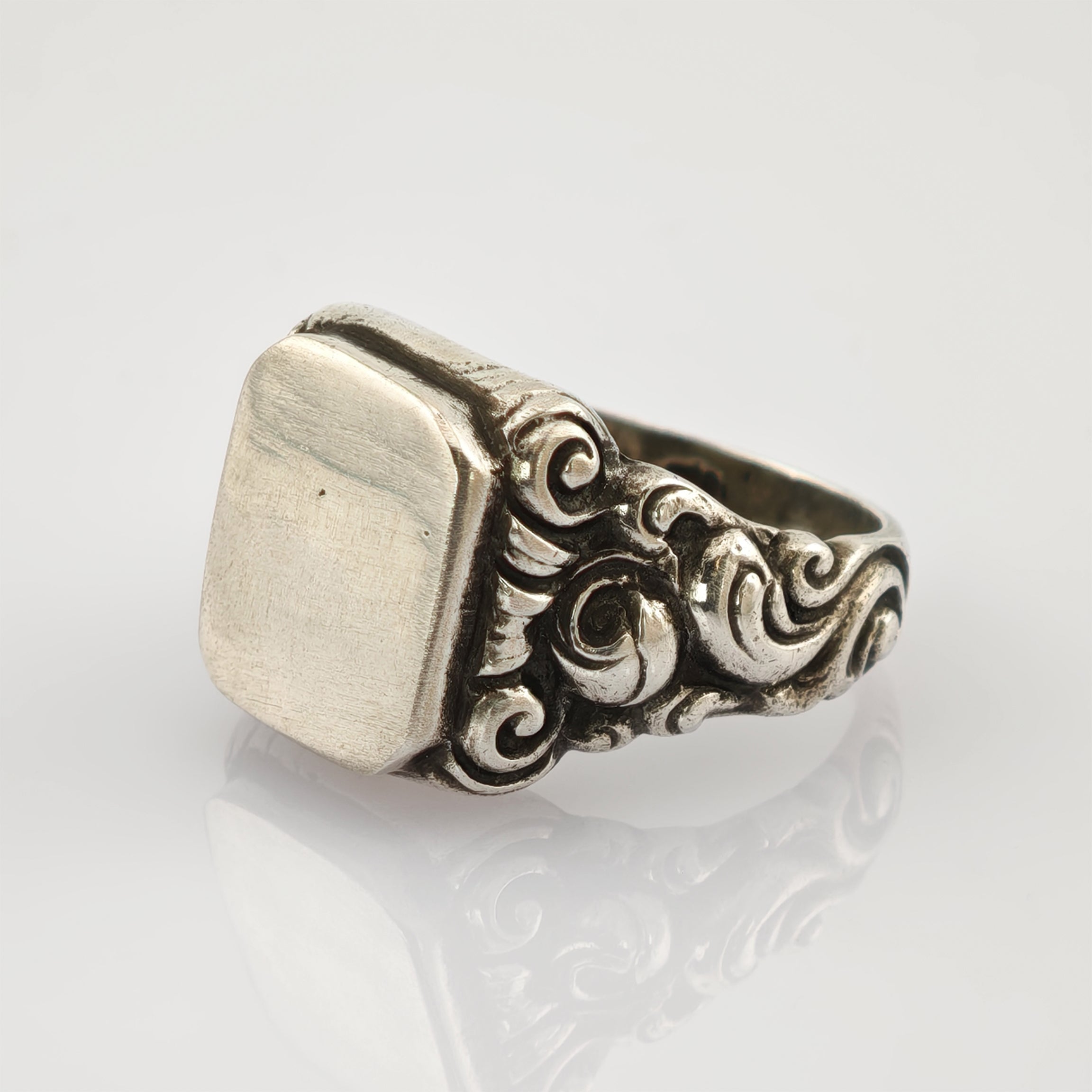 Silberner Vintage-Ring mit kunstvollen, gewundenen Details und rechteckiger, flacher Platine.