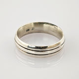 Silberner Vintage-Ring mit zwei parallel verlaufenden Rillen und leichter Patina auf weißem reflektierendem Untergrund.