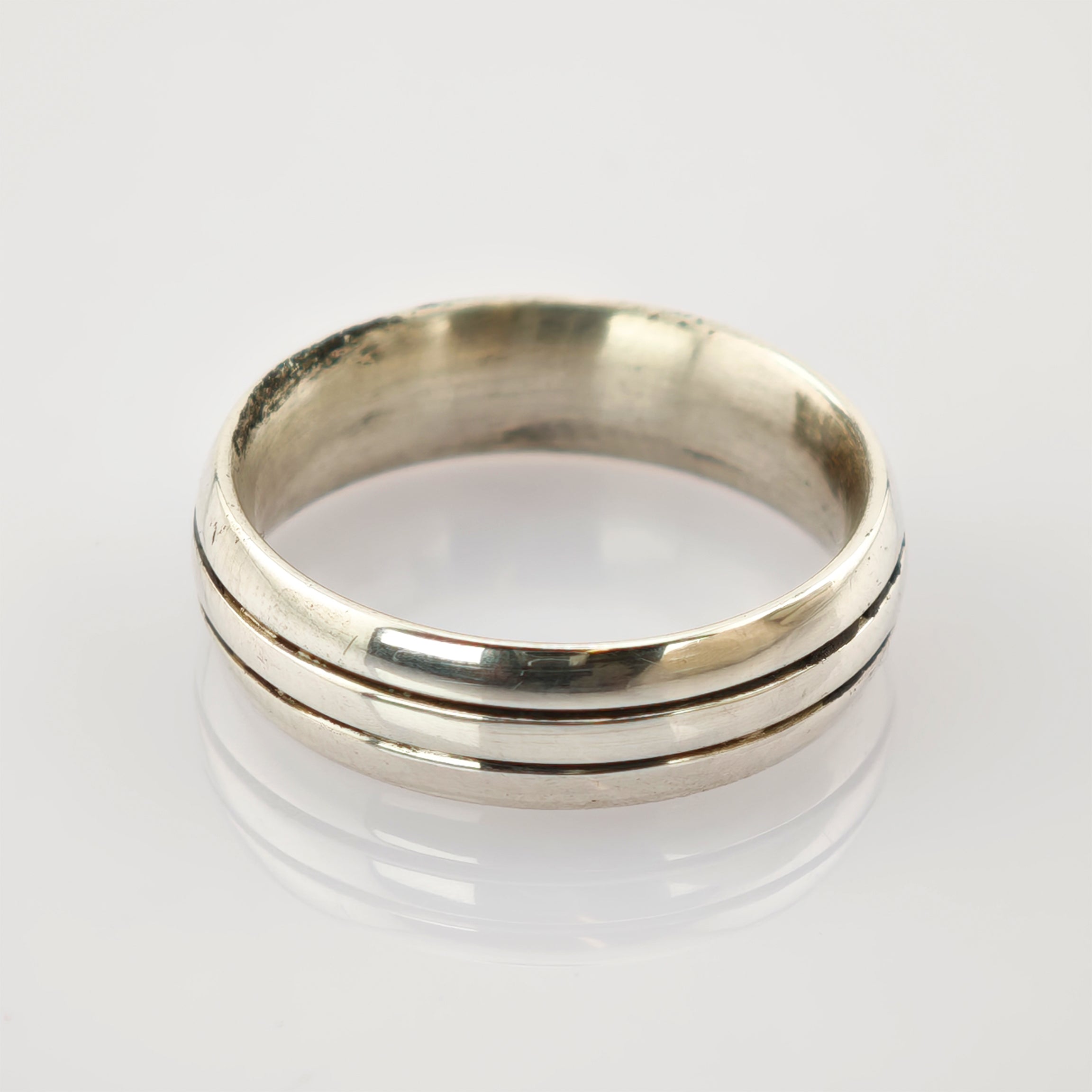 Silberner Vintage-Ring mit zwei parallelen Rillen auf reflektierender Oberfläche.