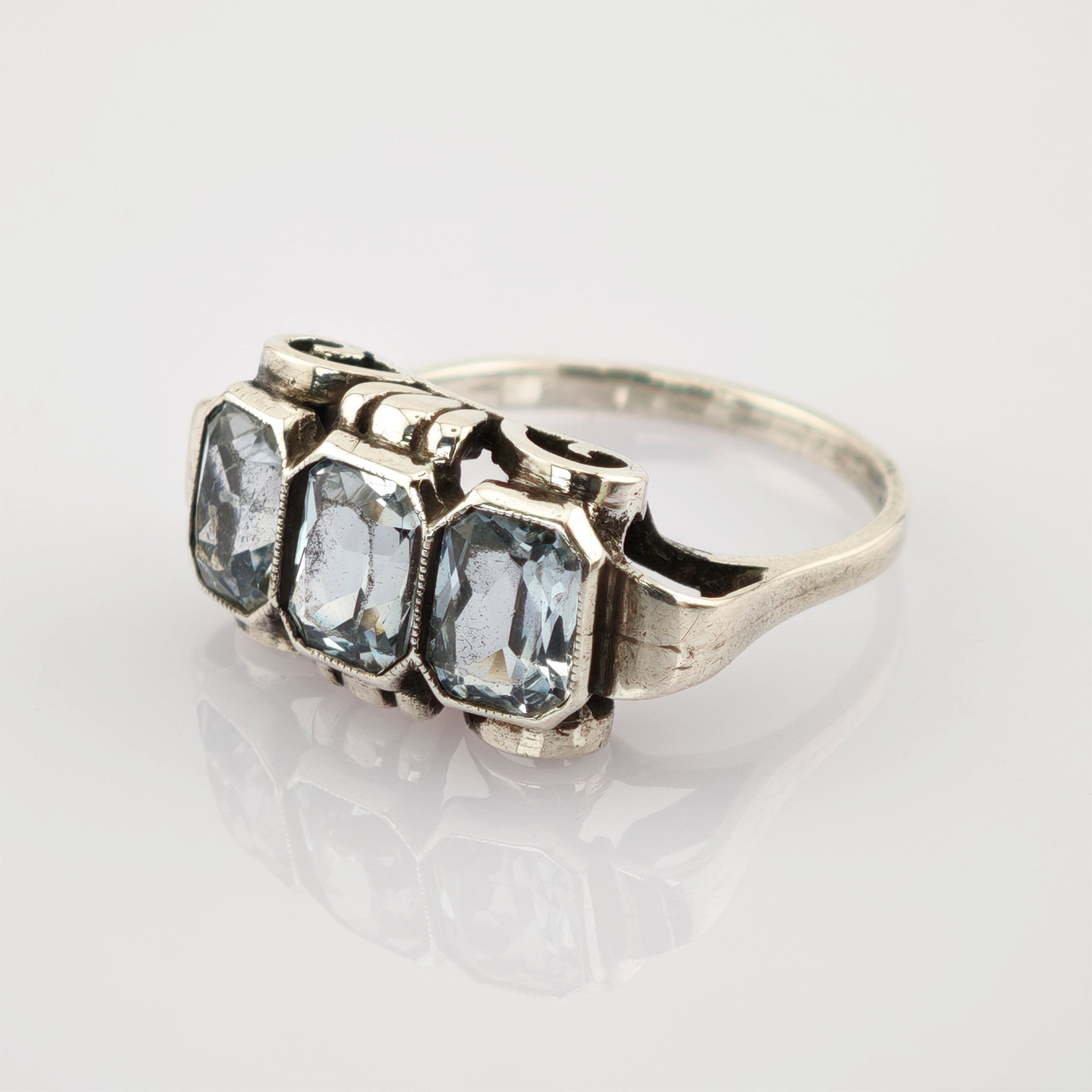 Silberner Vintage-Ring mit drei rechteckigen klaren Edelsteinen auf weißem Untergrund.