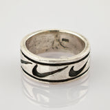 Silberner Vintage-Ring mit dunkel gefülltem Muster und Gebrauchsspuren auf reflektierender Oberfläche