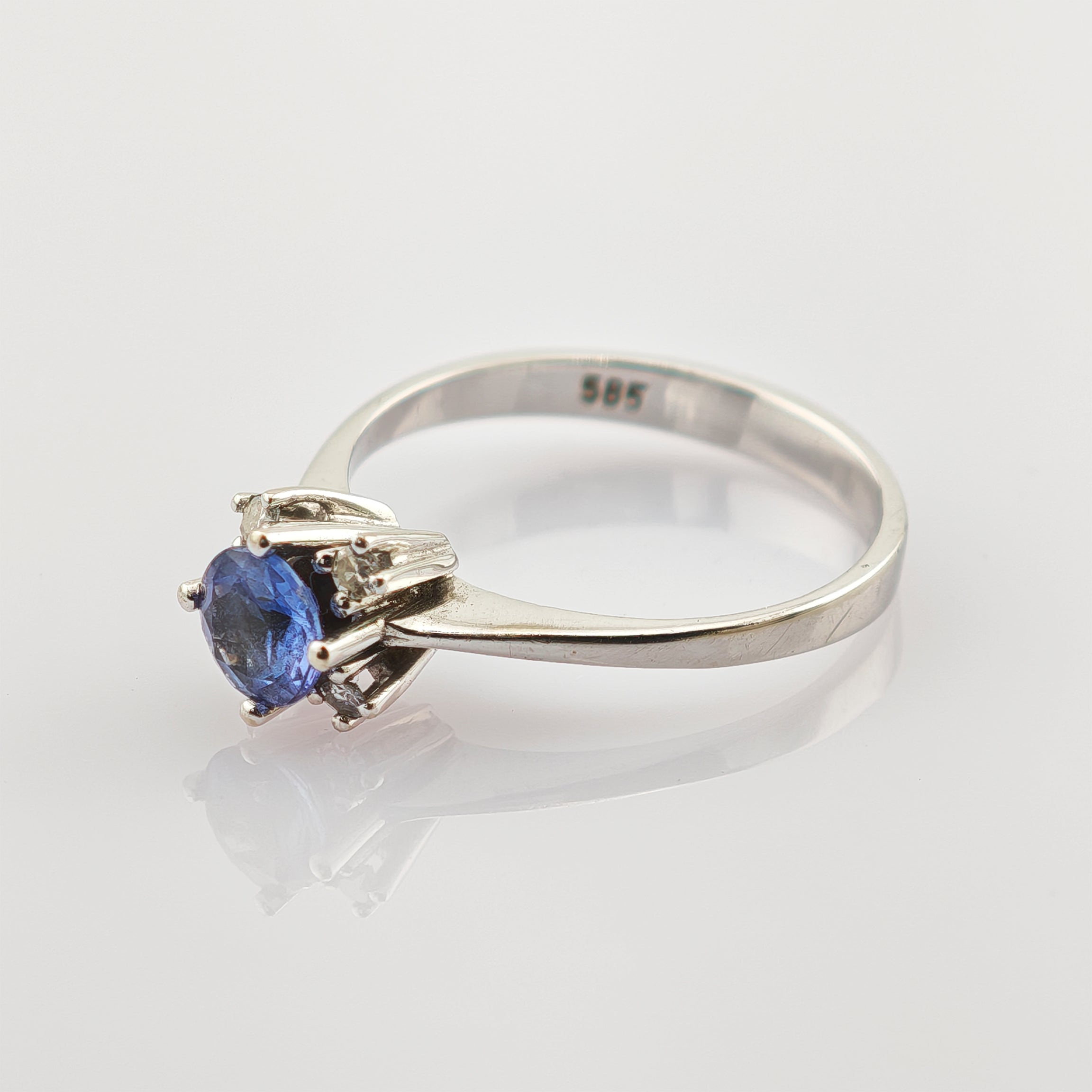 Silberring mit rundem blauen Edelstein und klaren Steinen auf reflektierendem Weiß