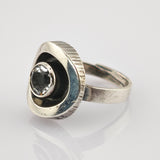 Silberring mit dreieckigem Oberteil und facettiertem, klarem Edelstein, trägt Kratzer und Patina.