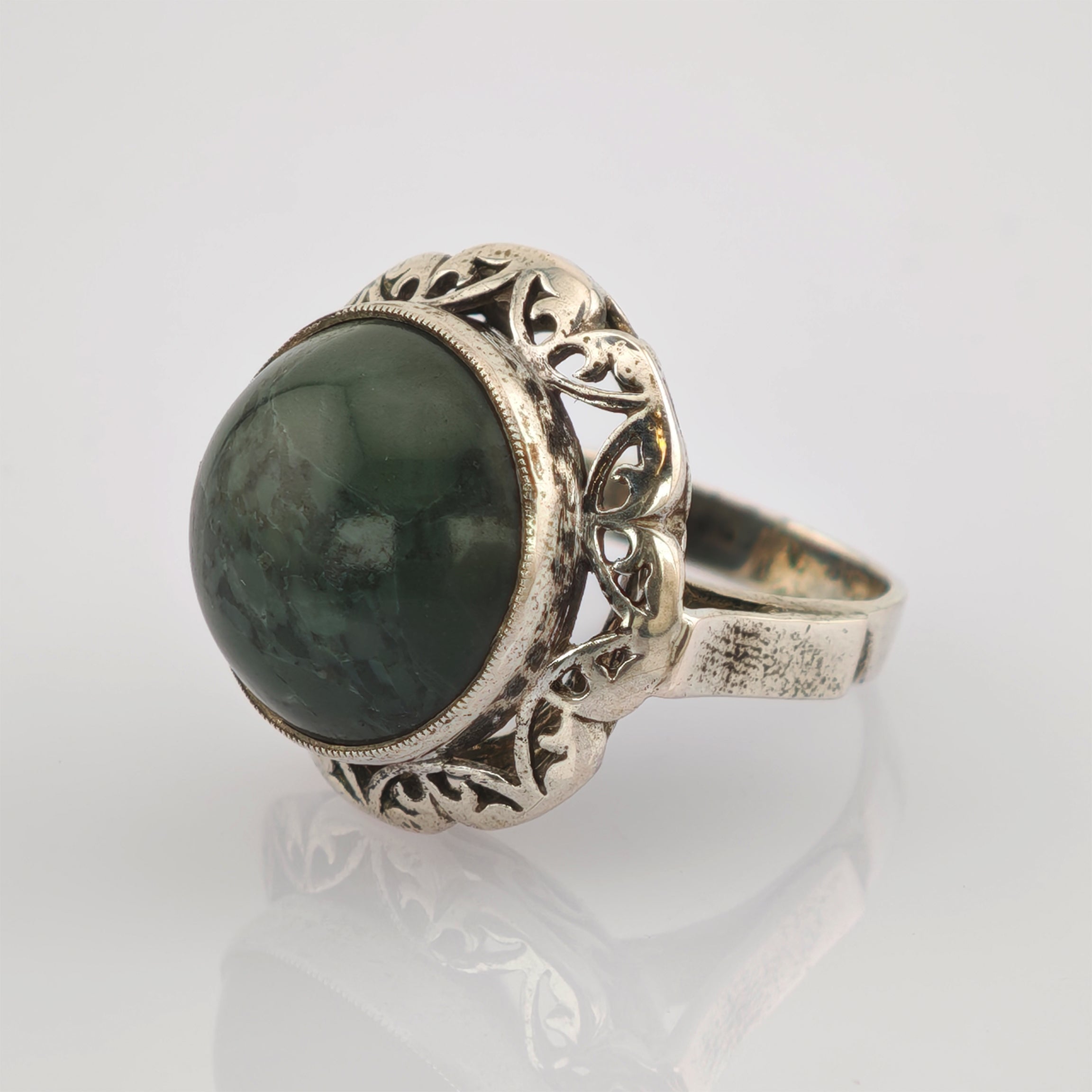 Eleganter Silberring mit kunstvoll gestaltetem Band und großem dunkelgrünem Edelstein.