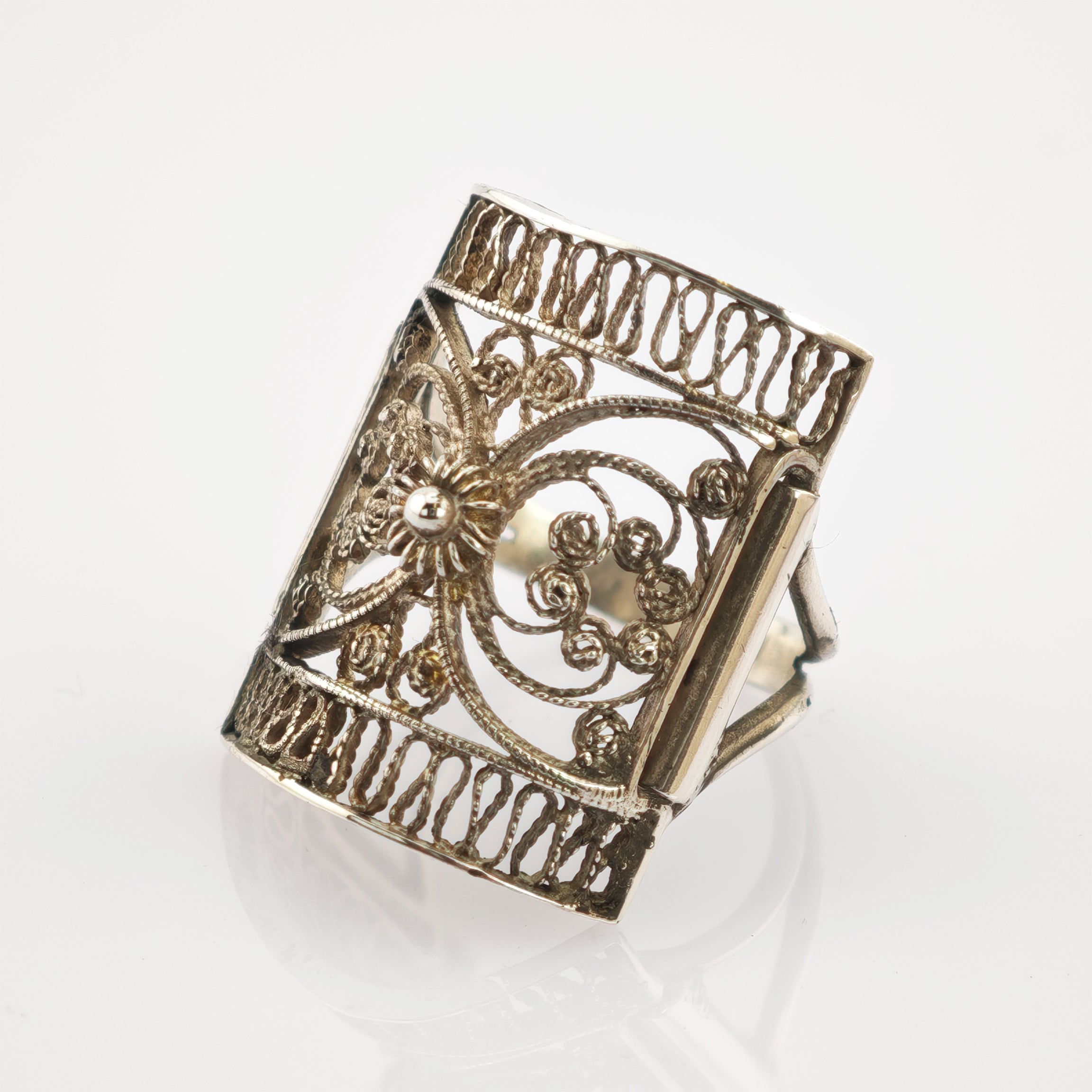 Detaillierter Silberring mit filigranem Blumenmotiv auf reflektierender weißer Oberfläche.