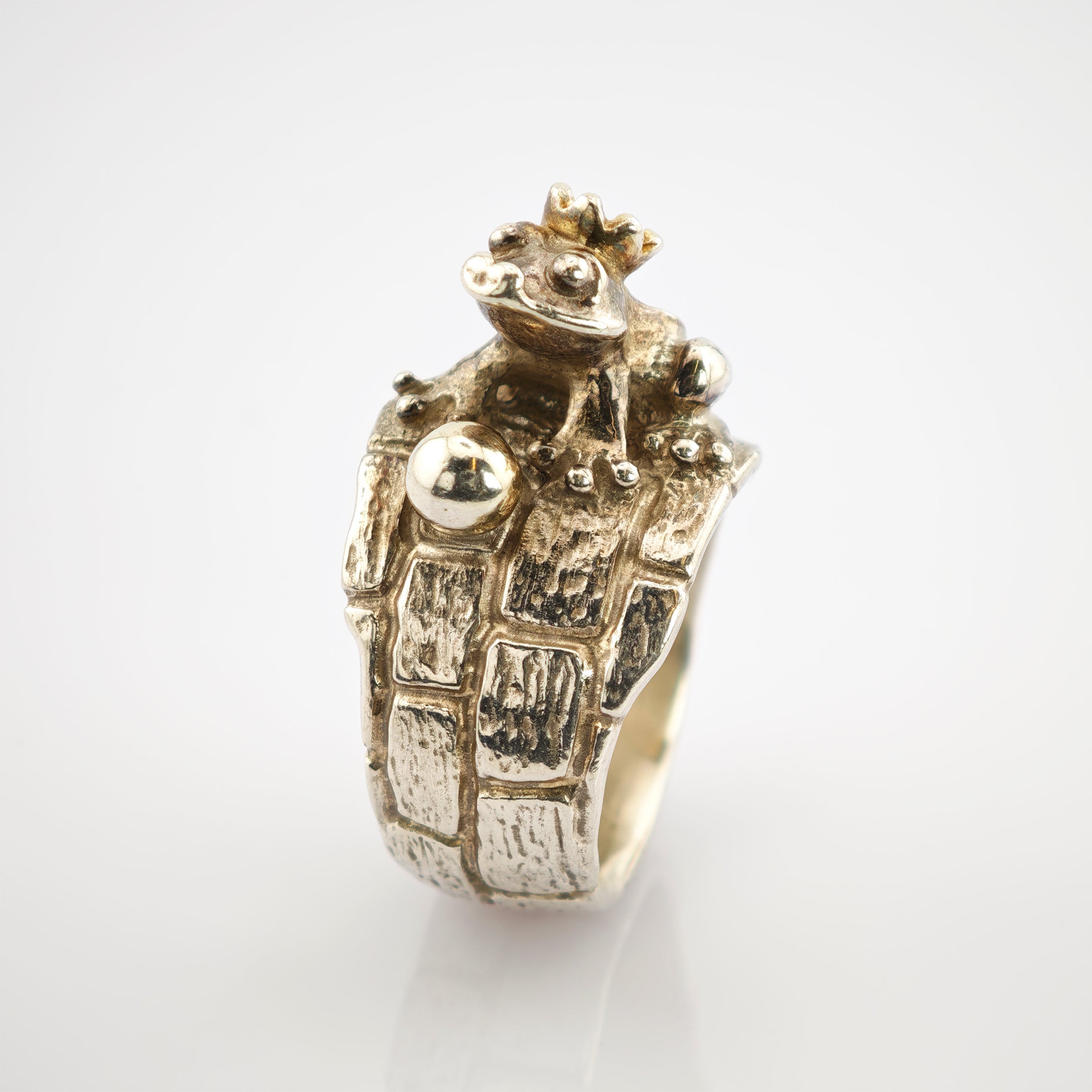 Silberring mit Froschdesign und Krone auf kopfsteinpflasterförmigem Band