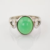 Silberring mit grünem ovalem Edelstein und durchbrochenem Band auf weißem Hintergrund