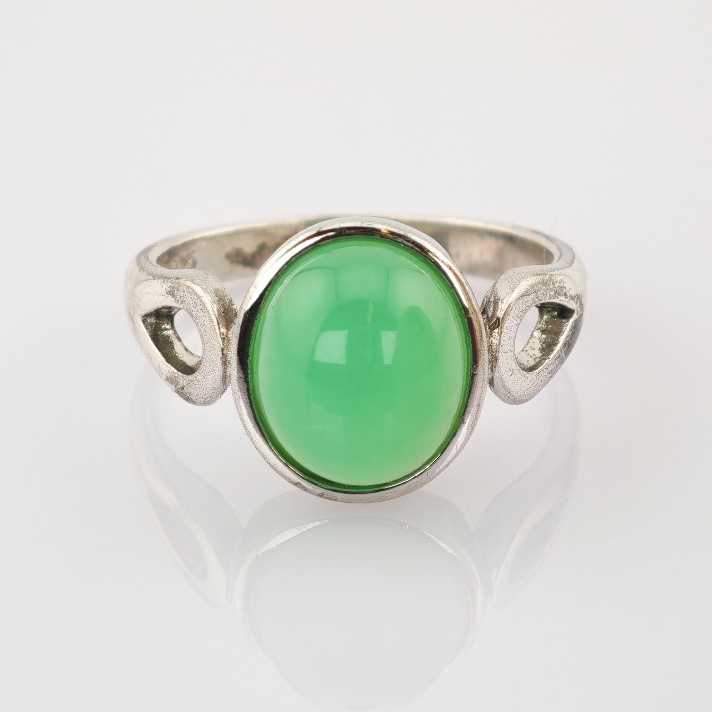 Silberring mit grünem ovalem Edelstein und durchbrochenem Band auf weißem Hintergrund