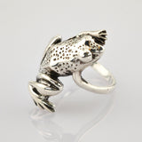 Silberring in Froschform mit texturiertem Rücken und glatten Beinen auf weißem Untergrund.