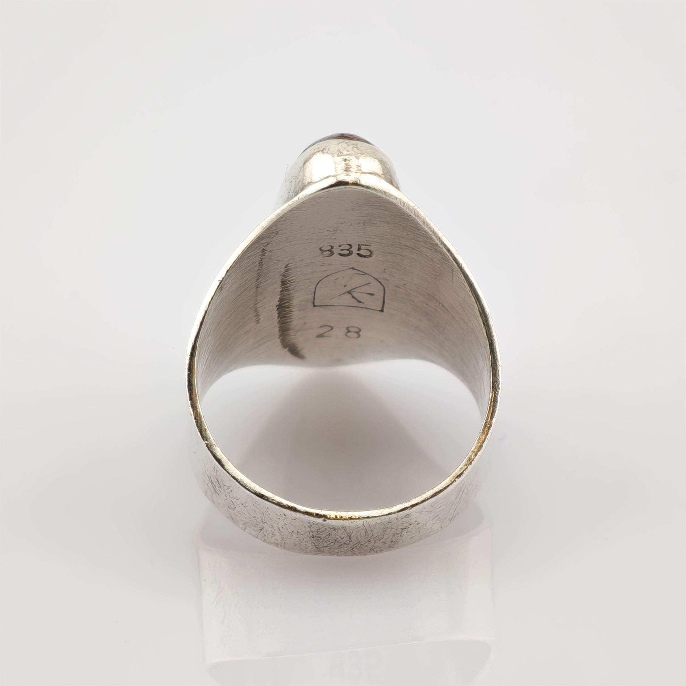 Innenansicht eines silbernen Rings mit eingravierter 835 Punze, stilisiertem K-Symbol und Nummer 28 auf weißem Hintergrund
