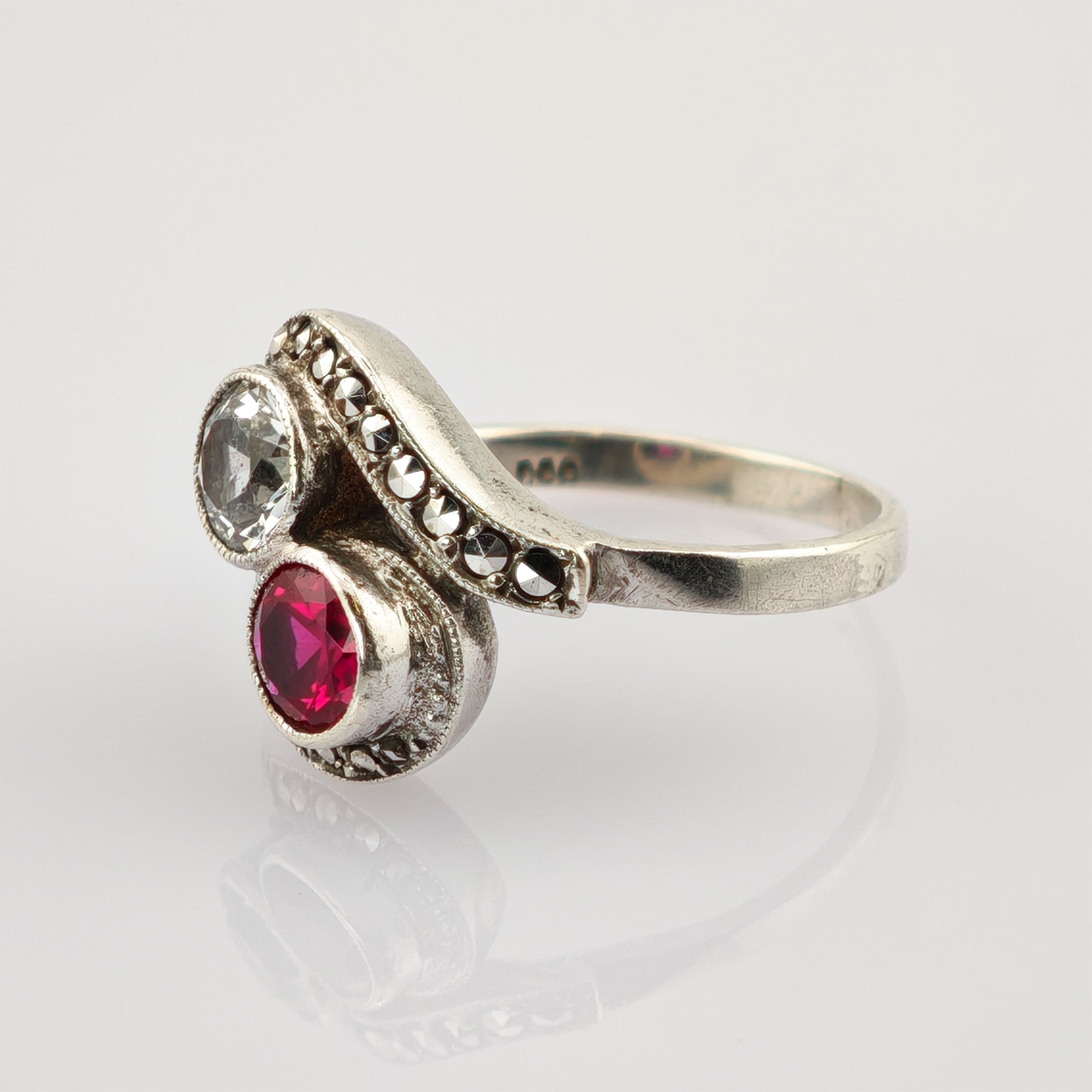 Eleganter Silberring mit großen klaren und roten Edelsteinen auf gewelltem Band mit Metallnieten