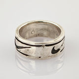 Silberner Vintage-Ring mit dunkel gefülltem Muster und Gebrauchsspuren auf reflektierender Oberfläche