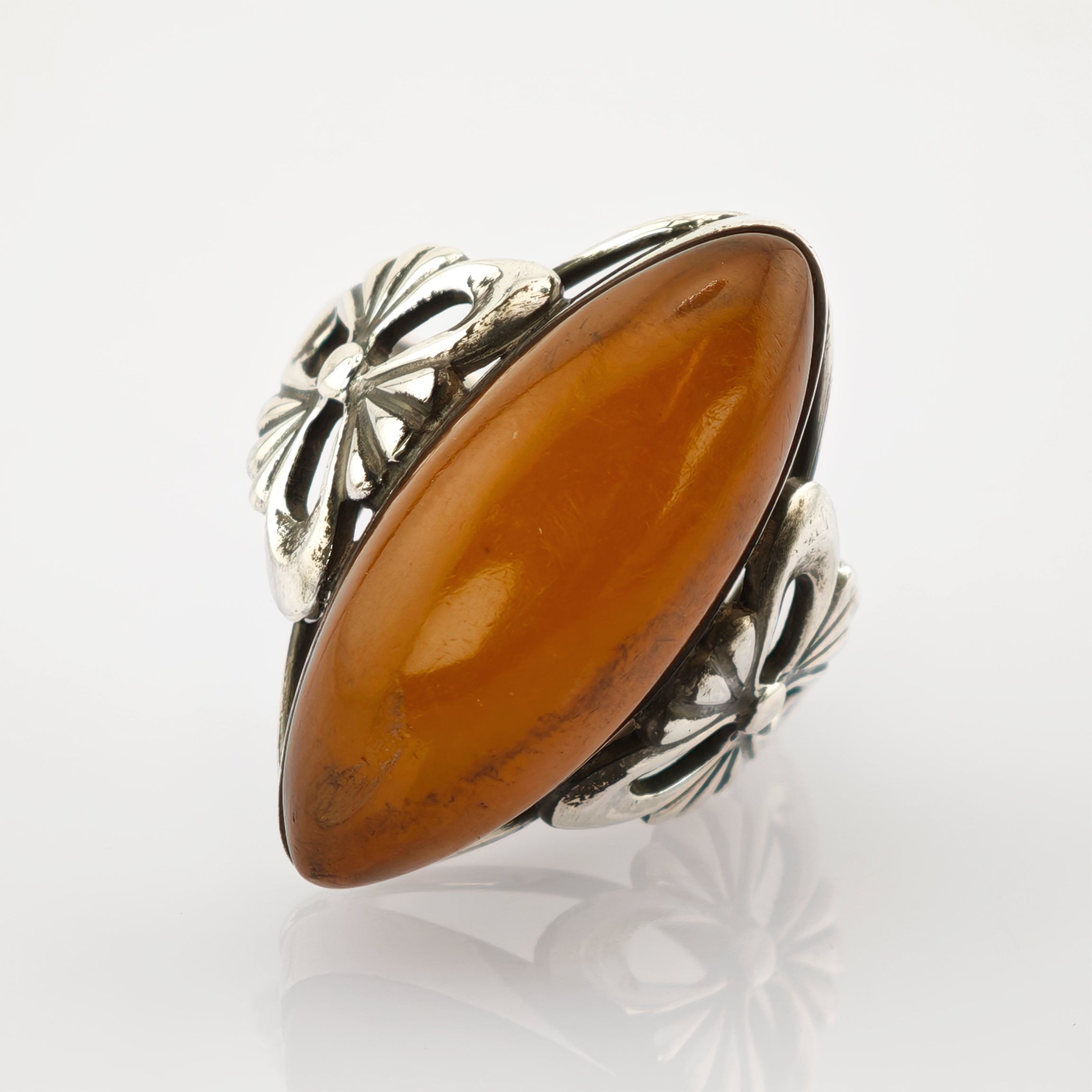 Silberring mit ovalem Bernstein und floralem Design auf weißem Hintergrund