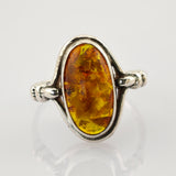 Silberring mit großem ovalem Bernstein in warmen Gelb- bis Orange-Tönen und Verzierungen am Ringband