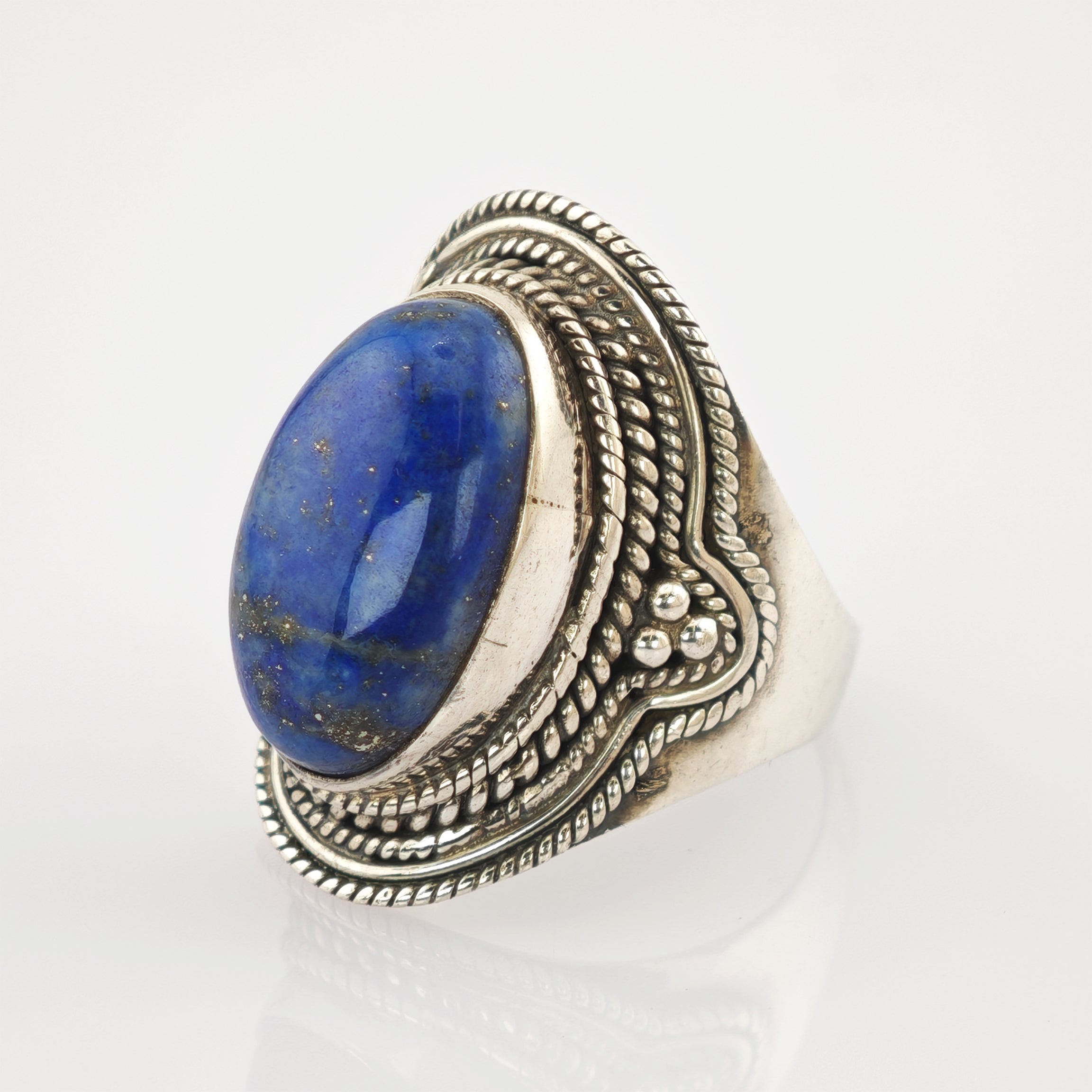 Silberring mit großem ovalem blauem Edelstein und kunstvollem Seil- und Perlenmuster.