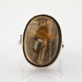 Silberring mit ovalem Cabochon-Stein und feinen goldenen Rutilnadeln im glatten Fassungsdesign.