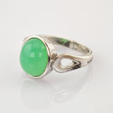 Silberring mit ovalem grünem Edelstein und tropfenförmigem Ausschnitt auf weißem Hintergrund