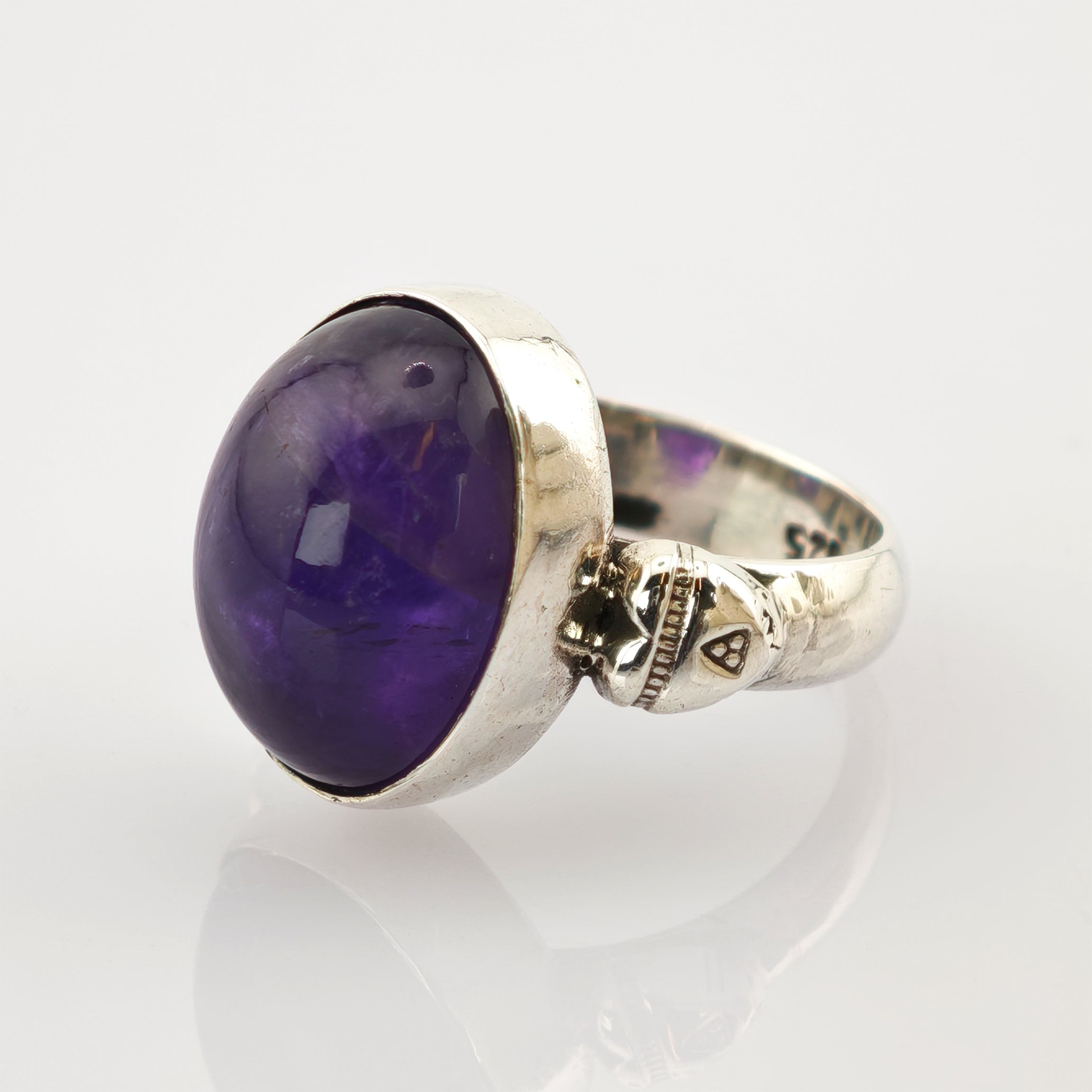 Silberring mit großem ovalem violettem Edelstein und kleinem Totenkopf an der Ringschiene.
