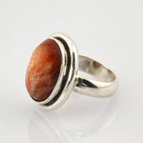 Silberring mit breitem poliertem Band und großem ovalem Cabochon in rötlich-brauner Zargenfassung