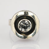 Silberring mit rundem klarem facettiertem Edelstein in konkaver Fassung und matter Oberfläche.