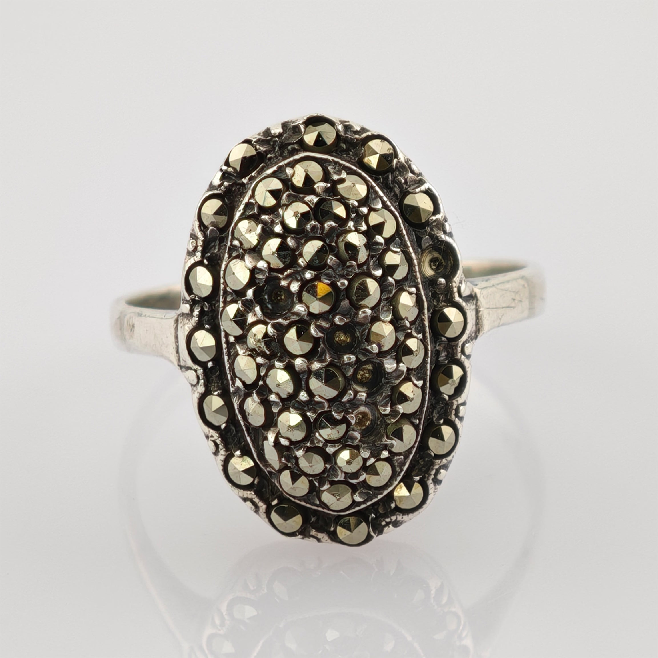 Silberring im Vintage-Stil mit ovalem Design und facettierten metallischen Steinen im Muster.