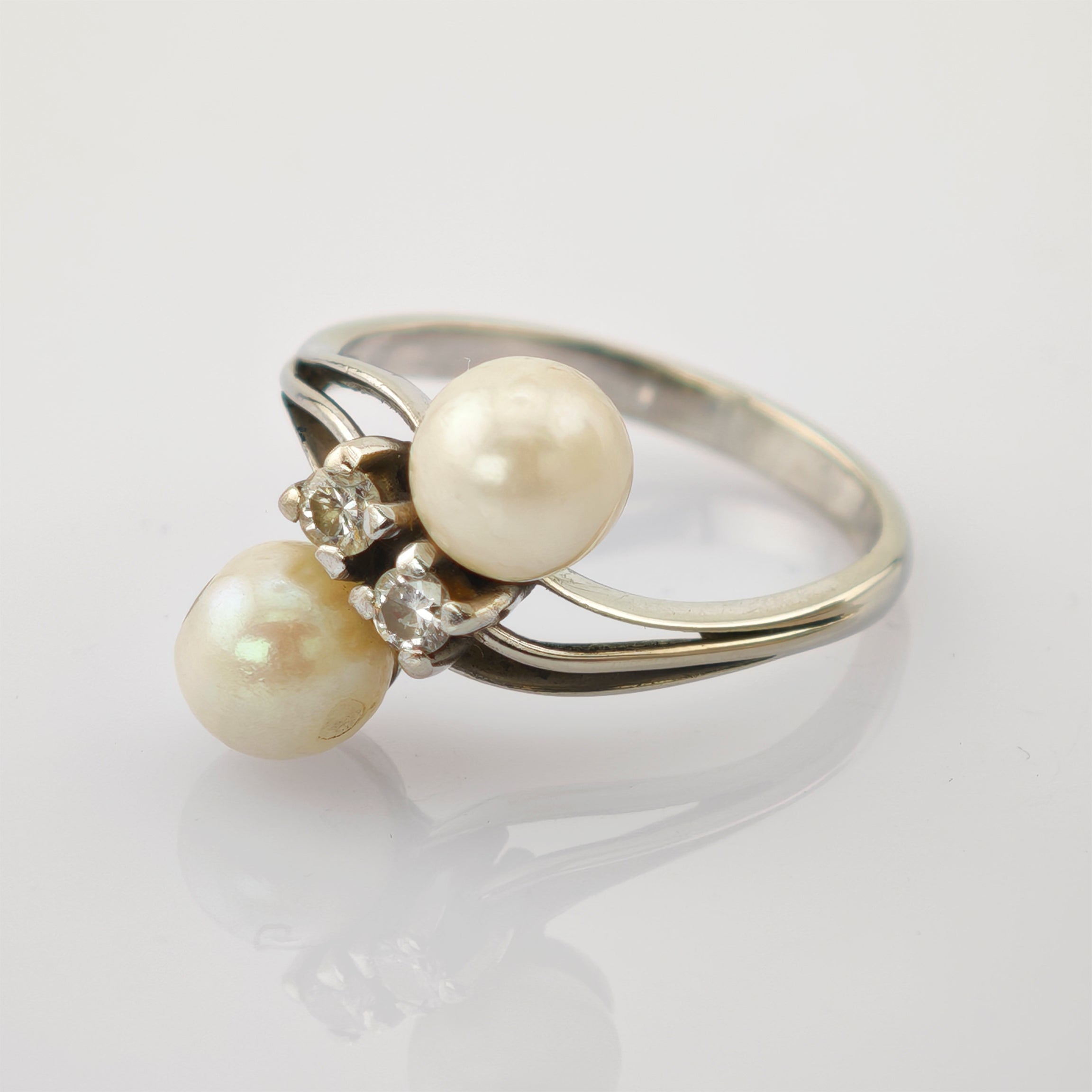 Eleganter Silberring mit zwei Perlen und kleinen klaren Steinen auf geteiltem Ringband.