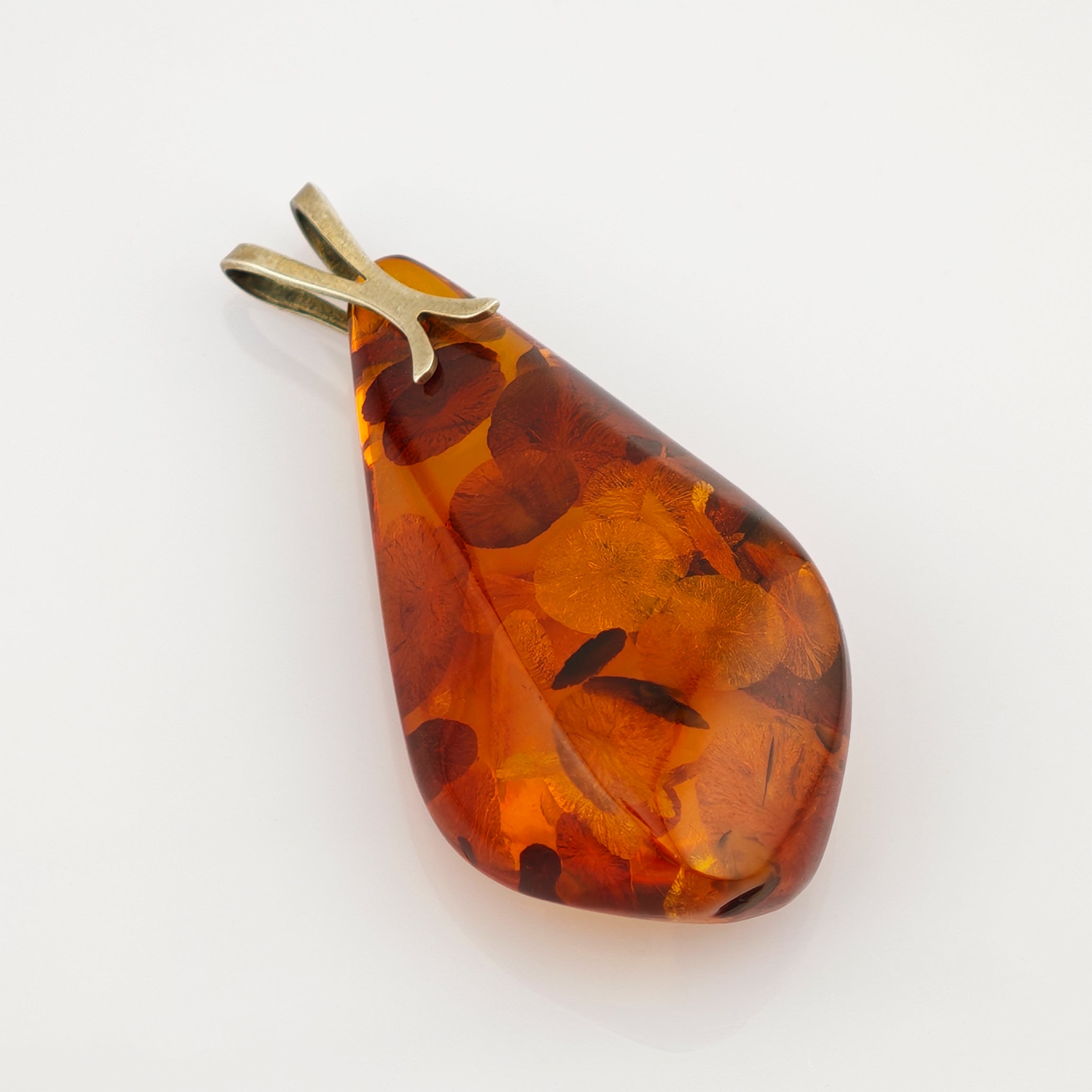 Tropfenförmiger Bernsteinanhänger mit natürlichen Einschlüssen und Metallöse auf weißem Hintergrund