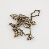 Verknotete silberfarbene Kette mit rundem Federverschluss und ovalem Anhänger auf weißem Hintergrund