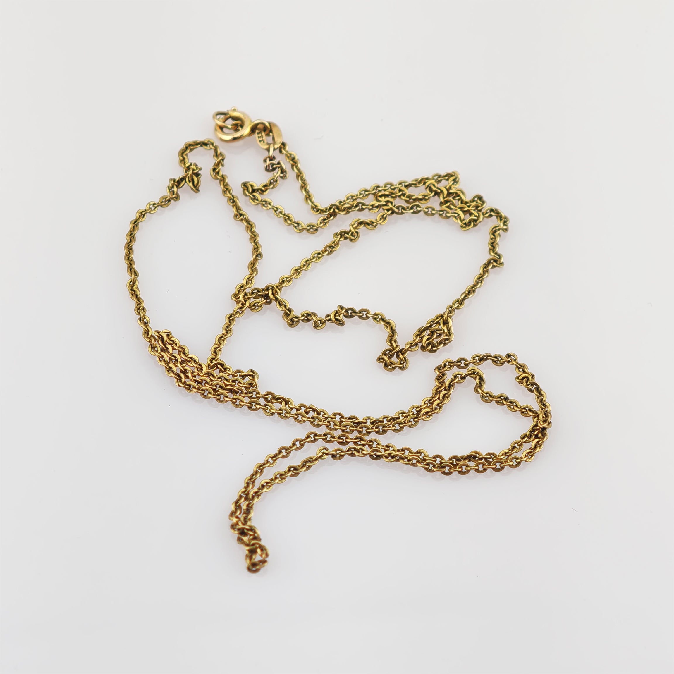 Verwickelte goldene Halskette mit feinem Gliederdesign und kleinem Verschluss auf weißem Hintergrund