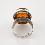 Vintage-Silberring mit bernsteinfarbenem Stein und verstellbarem Band auf weißem Hintergrund