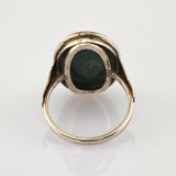 Vintage Silberring mit dunkelgrünem ovalem Edelstein und kunstvoller Fassung auf weißem Hintergrund.