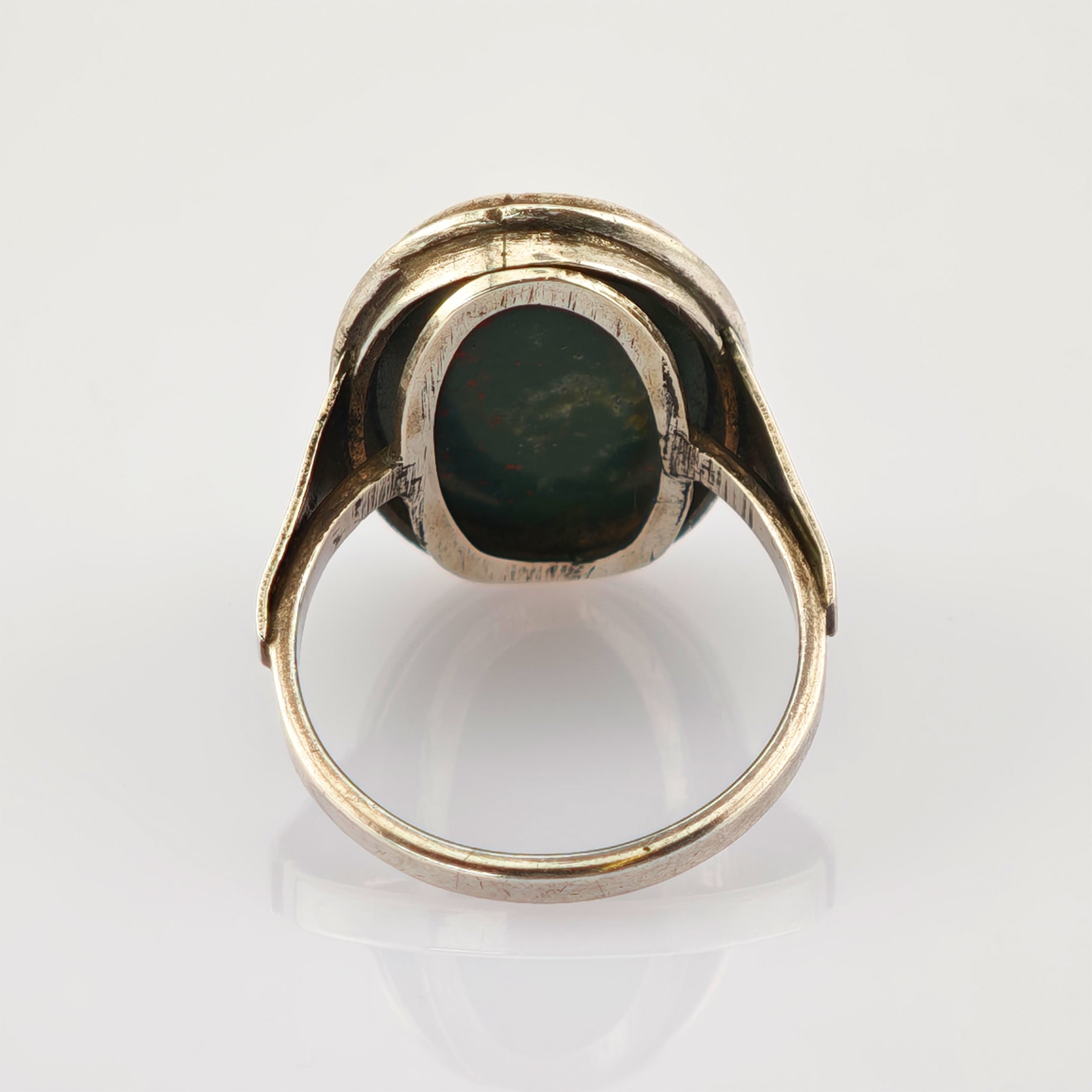 Vintage Silberring mit dunkelgrünem ovalem Edelstein und kunstvoller Fassung auf weißem Hintergrund.