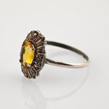 Vintage-Silberring mit ovalem gelbem Edelstein in kunstvoller Fassung auf weißem Hintergrund