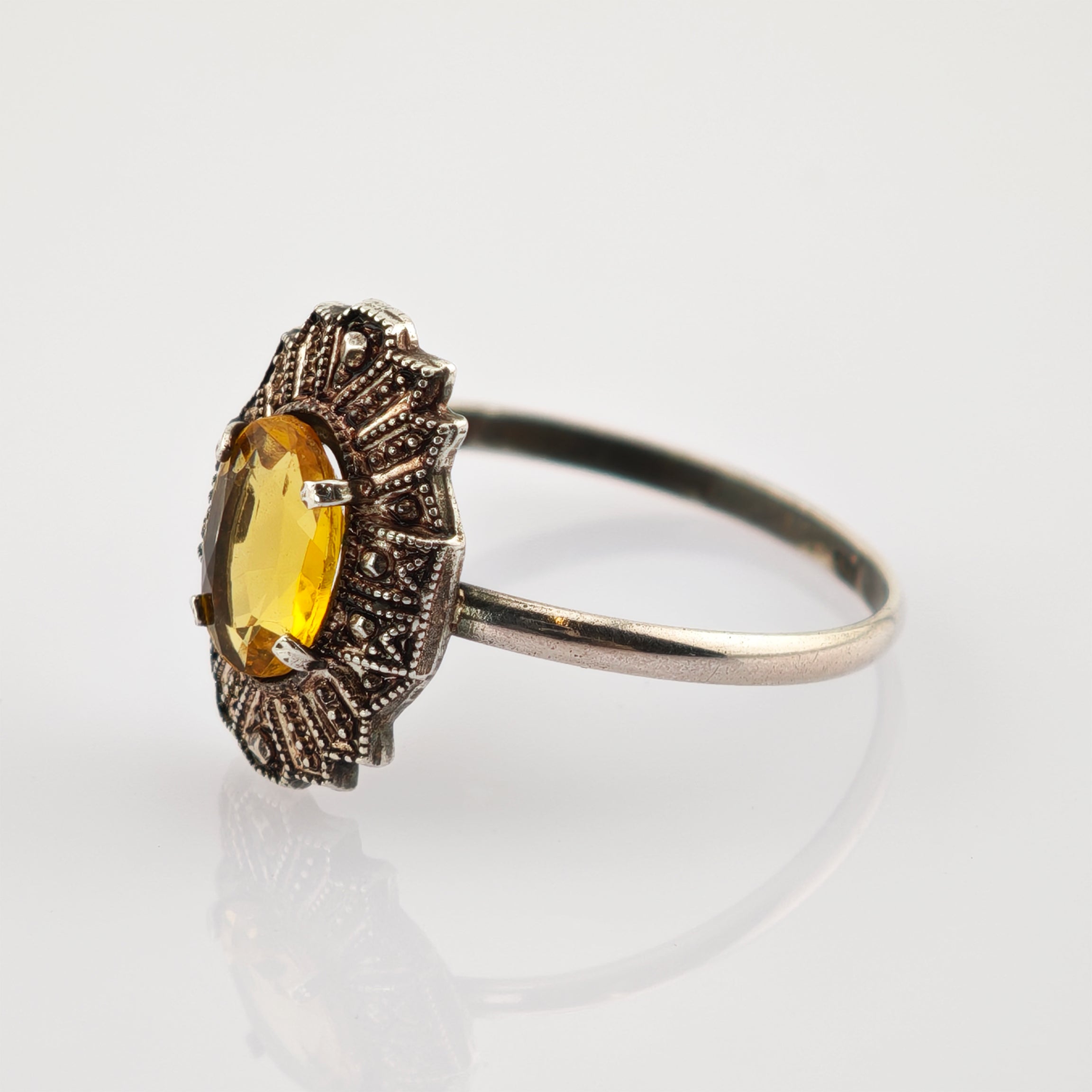 Vintage-Silberring mit ovalem gelbem Edelstein in kunstvoller Fassung auf weißem Hintergrund