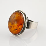 Vintage Silberring mit ovalem Bernstein und natürlichen Einschlussmustern auf angelaufenem Band.