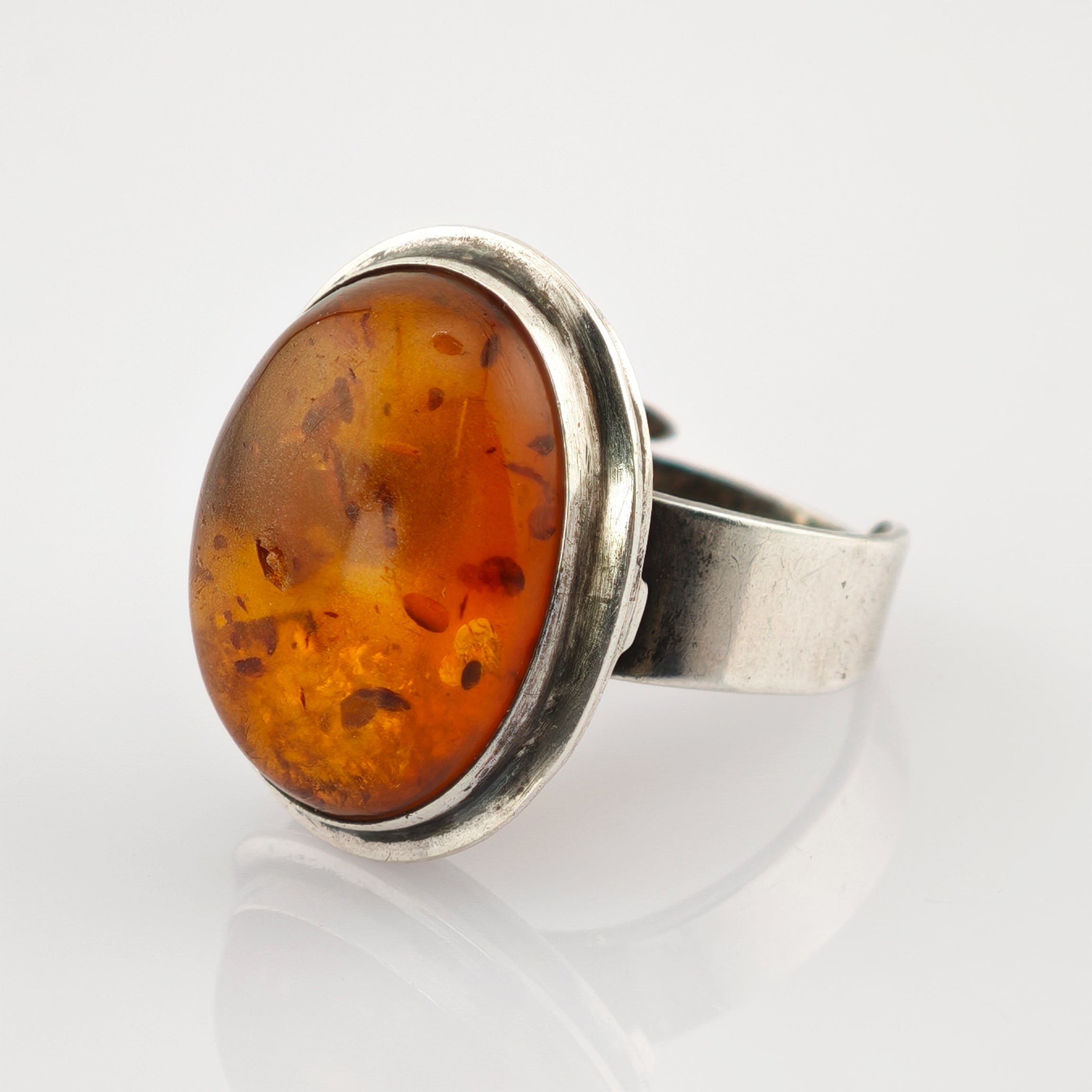 Vintage Silberring mit ovalem Bernstein und natürlichen Einschlussmustern auf angelaufenem Band.