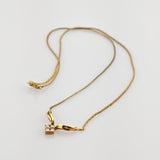 Zarte Goldkette mit einem einzigartigen Anhänger aus gebogenen Goldelementen und Diamantencluster.