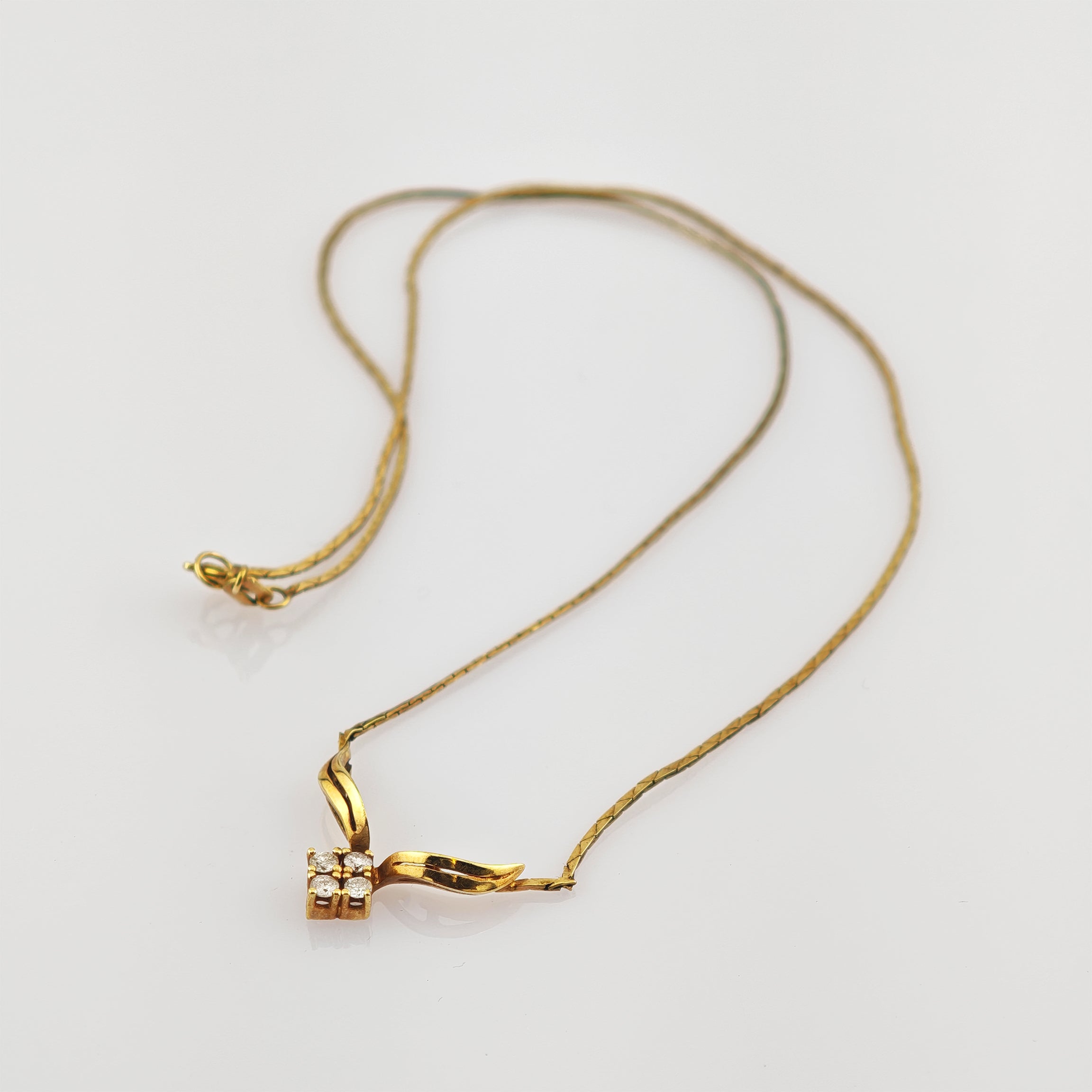 Zarte Goldkette mit einem einzigartigen Anhänger aus gebogenen Goldelementen und Diamantencluster.