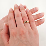 Zwei Hände aufeinandergelegt, eine mit Goldring und schwarzem Stein am Ringfinger, vor weißem Hintergrund.